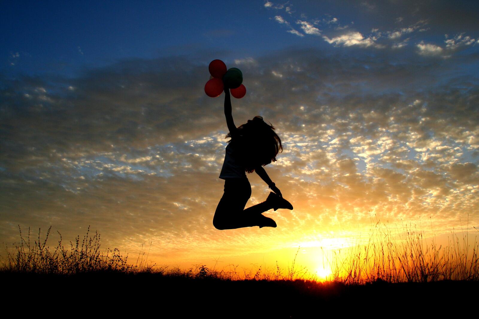 免费照片夕阳下的女孩跳起气球的剪影