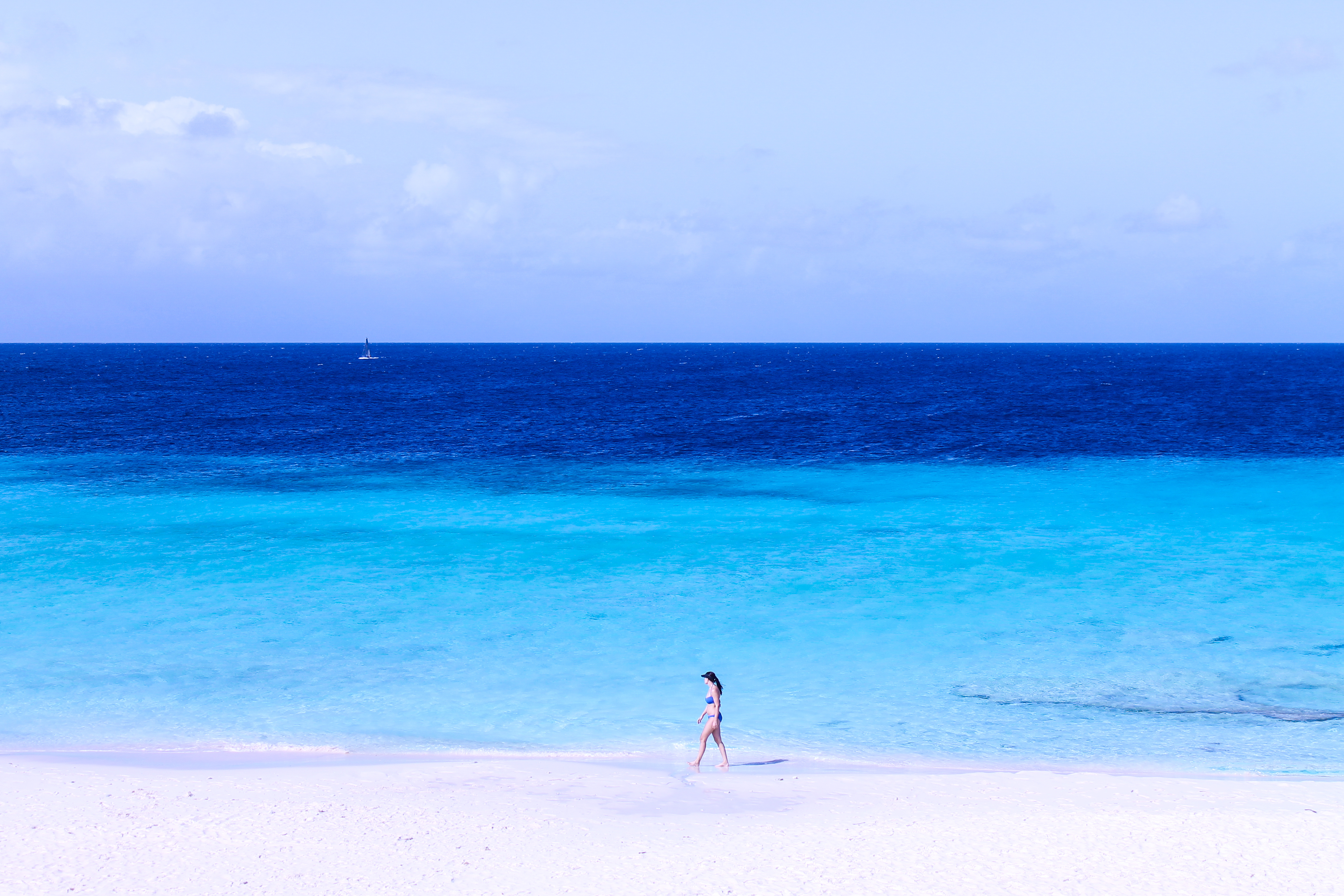 Девушка идет по песочному пляжу на берегу моря в кепке