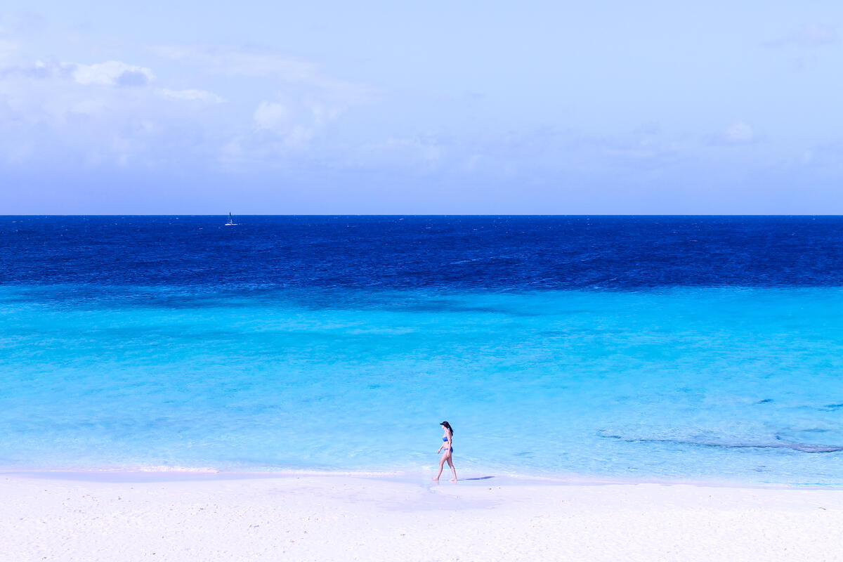 Девушка идет по песочному пляжу на берегу моря в кепке