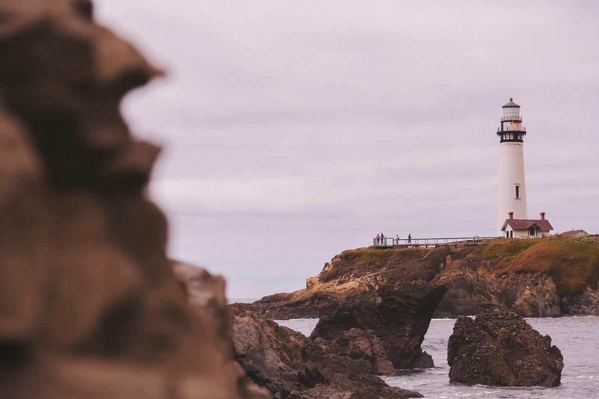 秋天的灯塔在阴天的岩石海岸上