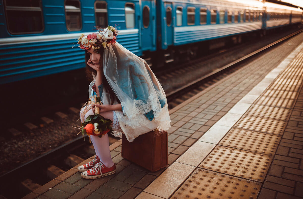 A girl on the platform sits on a suitcase