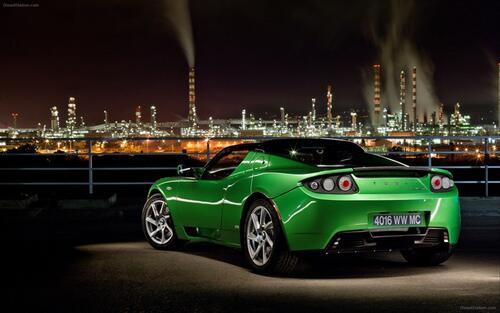 A green Lotus Evora against the backdrop of the city at night