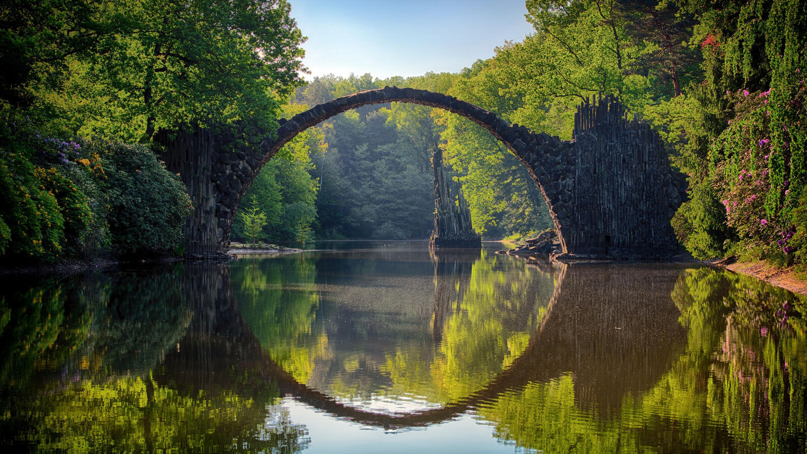 Free photo A large stone bridge over a lake in the woods