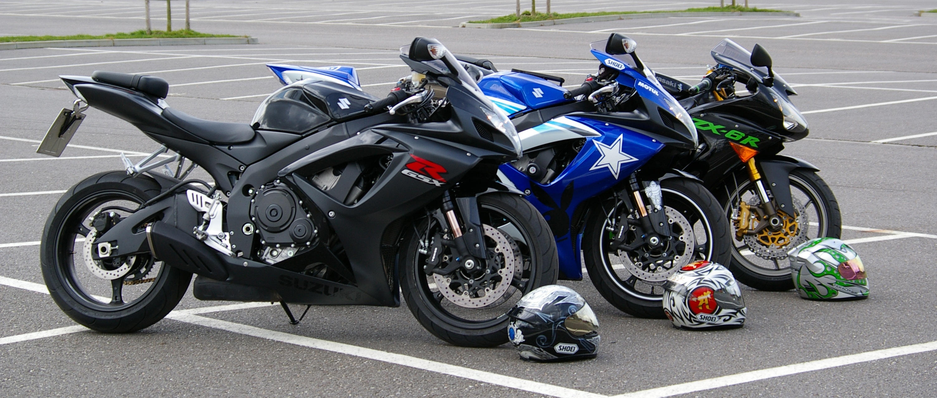 Free photo Three Kawasaki motorcycles in a parking lot.