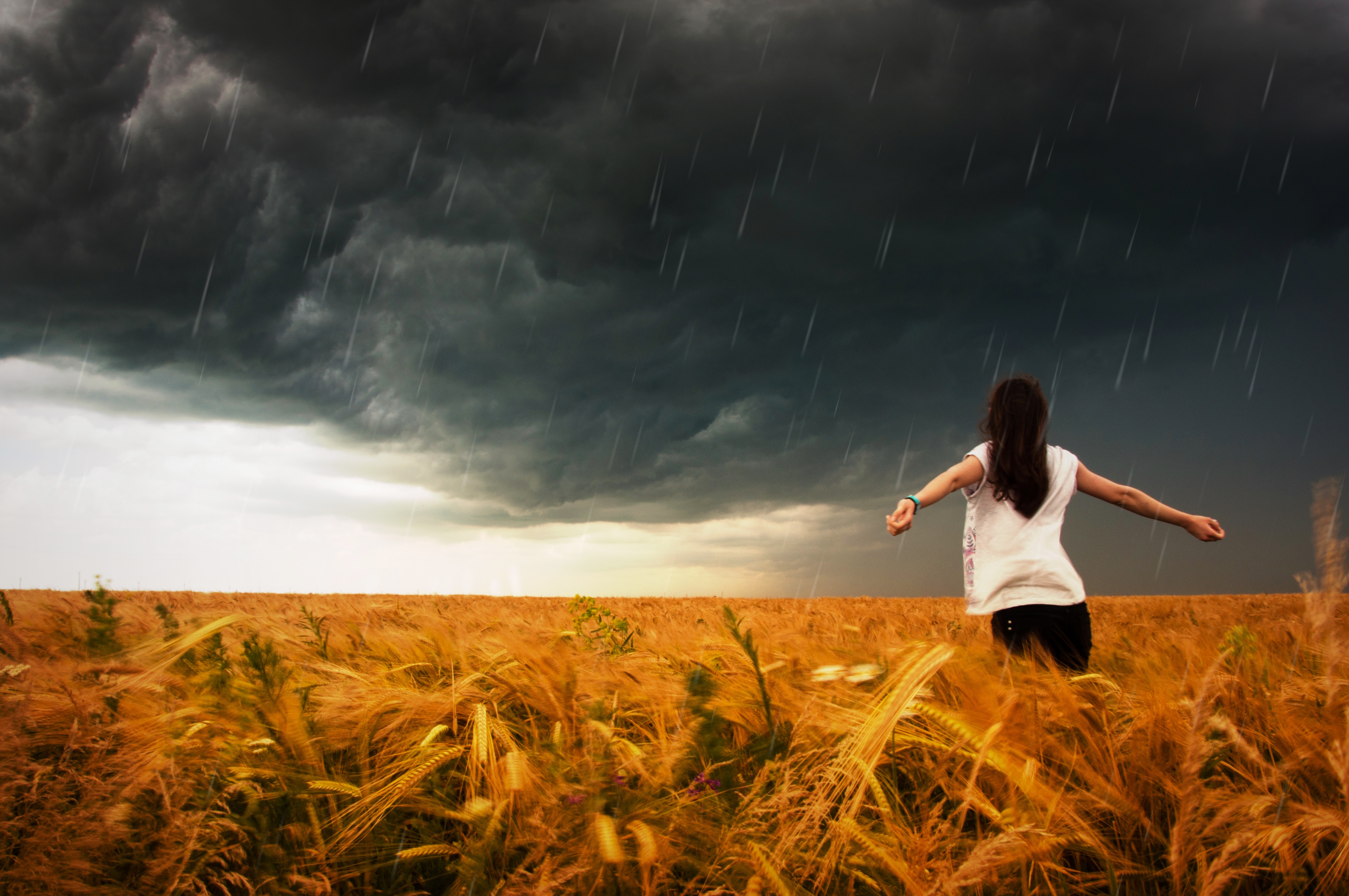 一个女孩在田野里享受雨水。