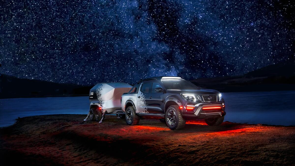 Nissan Navara с прицепом стоит на краю скалы на фоне ночного неба со звездами