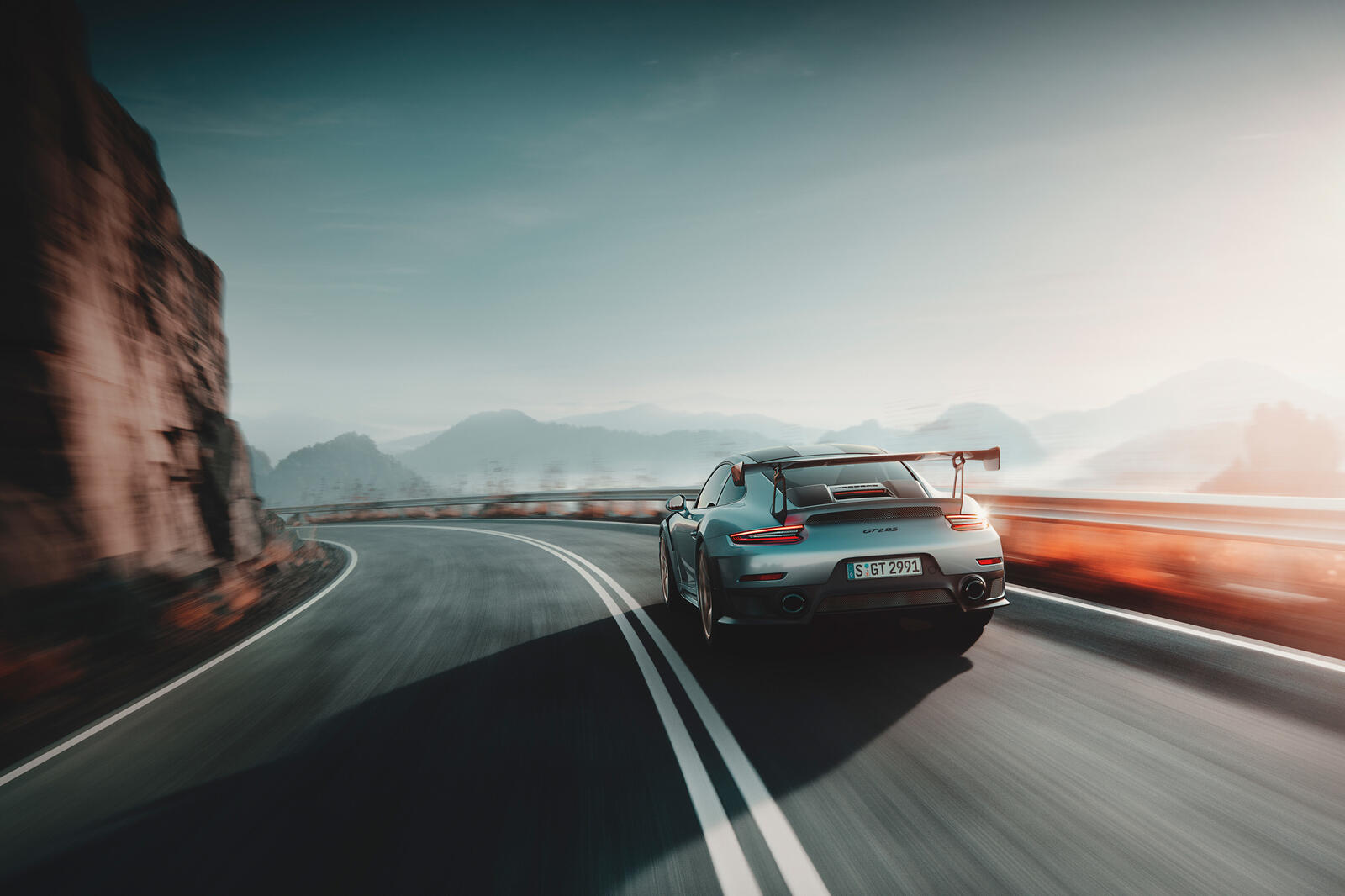 Бесплатное фото Серебристый Porsche 911 Gt2 мчится по дороге на обрыве горы