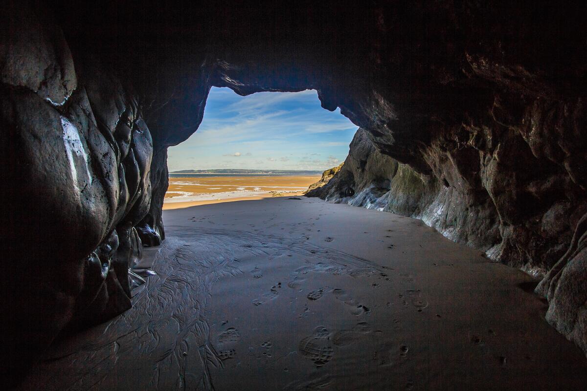 A cave with wet sand underfoot.