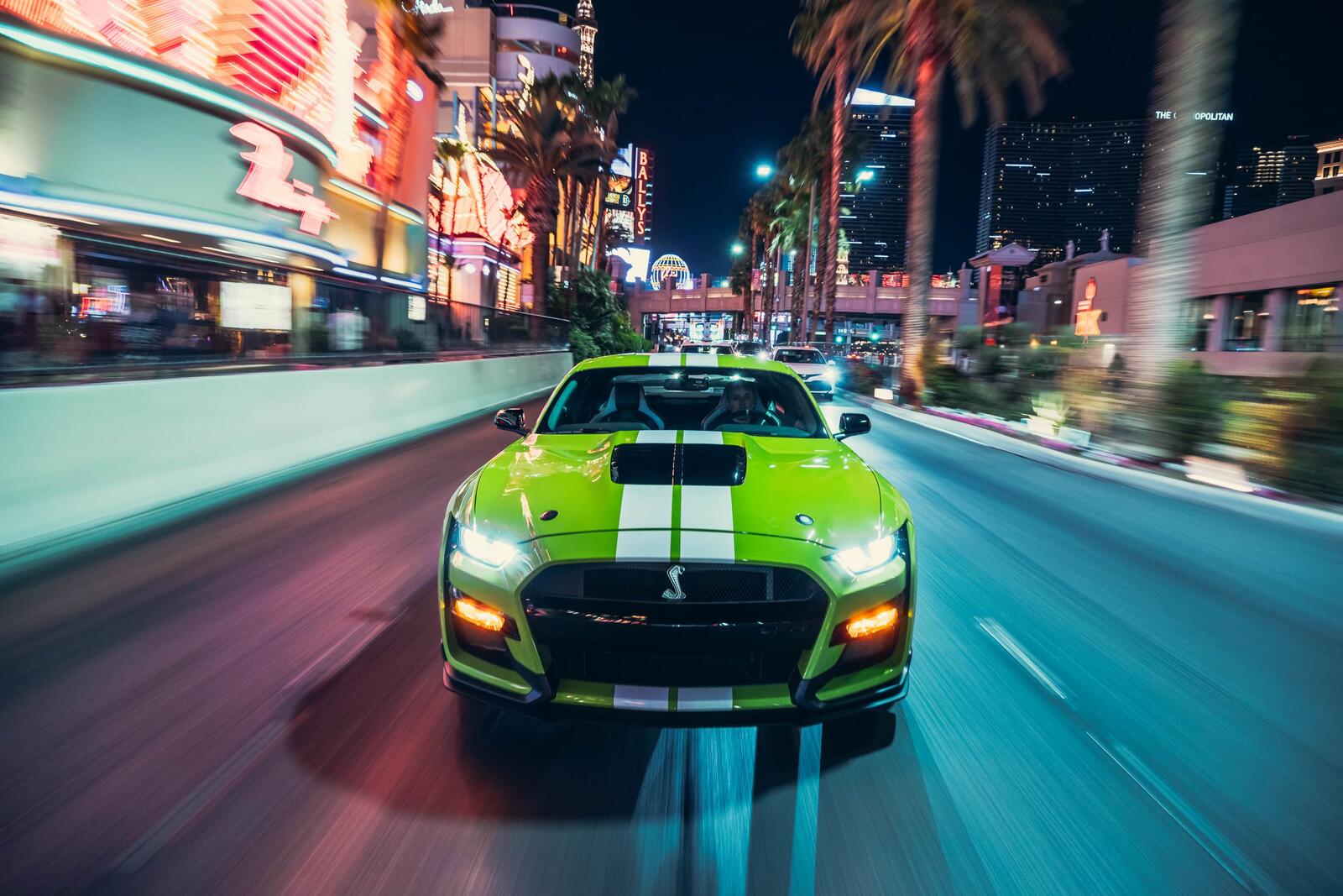 Бесплатное фото Салатовый Ford Mustang едет по ночной улице