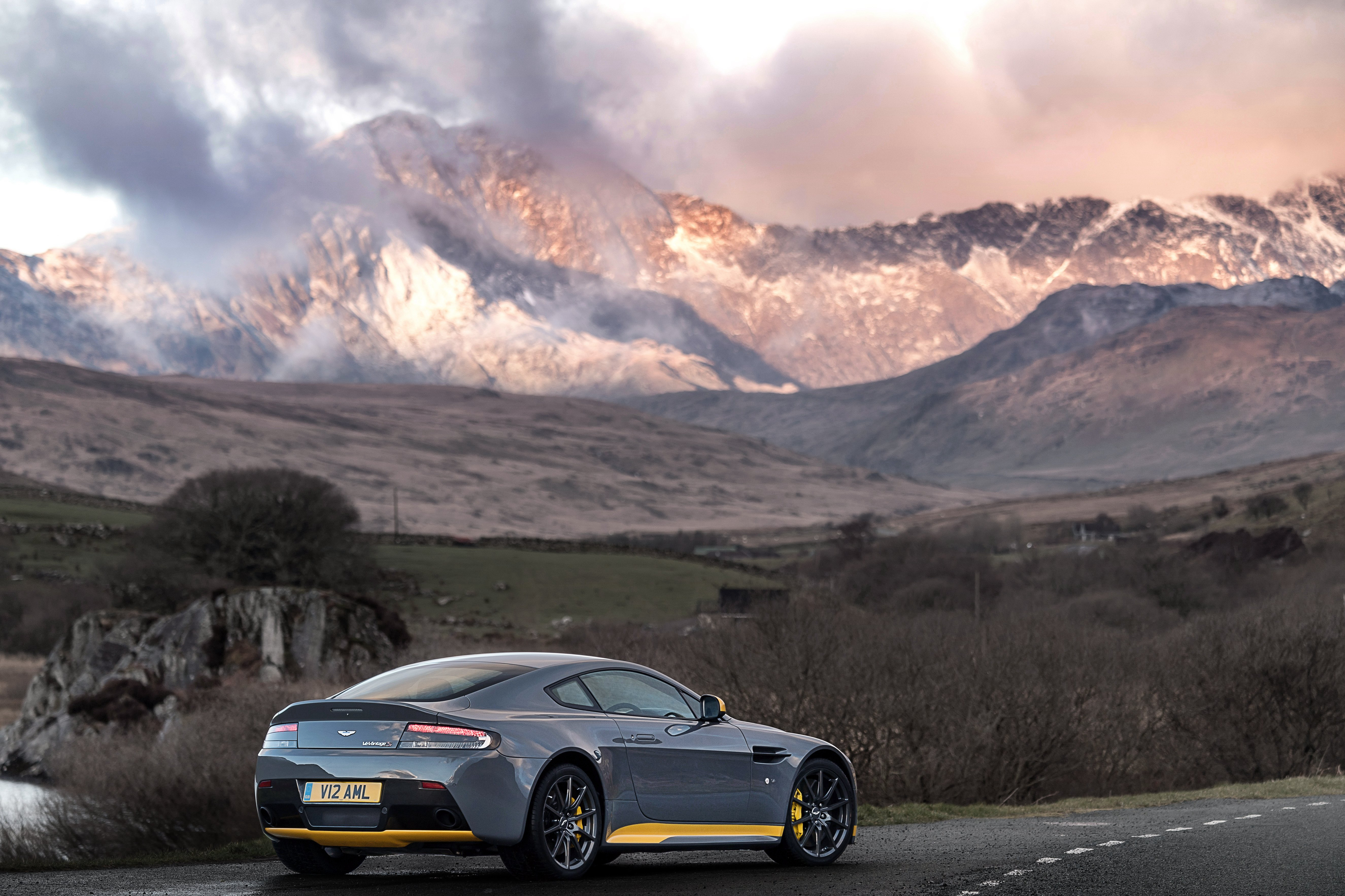 Серый Aston Martin V12 Vantage S на фоне гор
