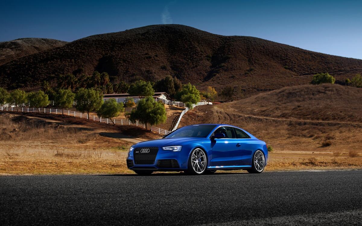 A blue Audi rs5 against a backdrop of rolling hills.