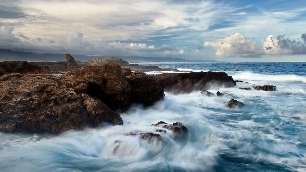 Волны разбиваются о скалы на берегу моря