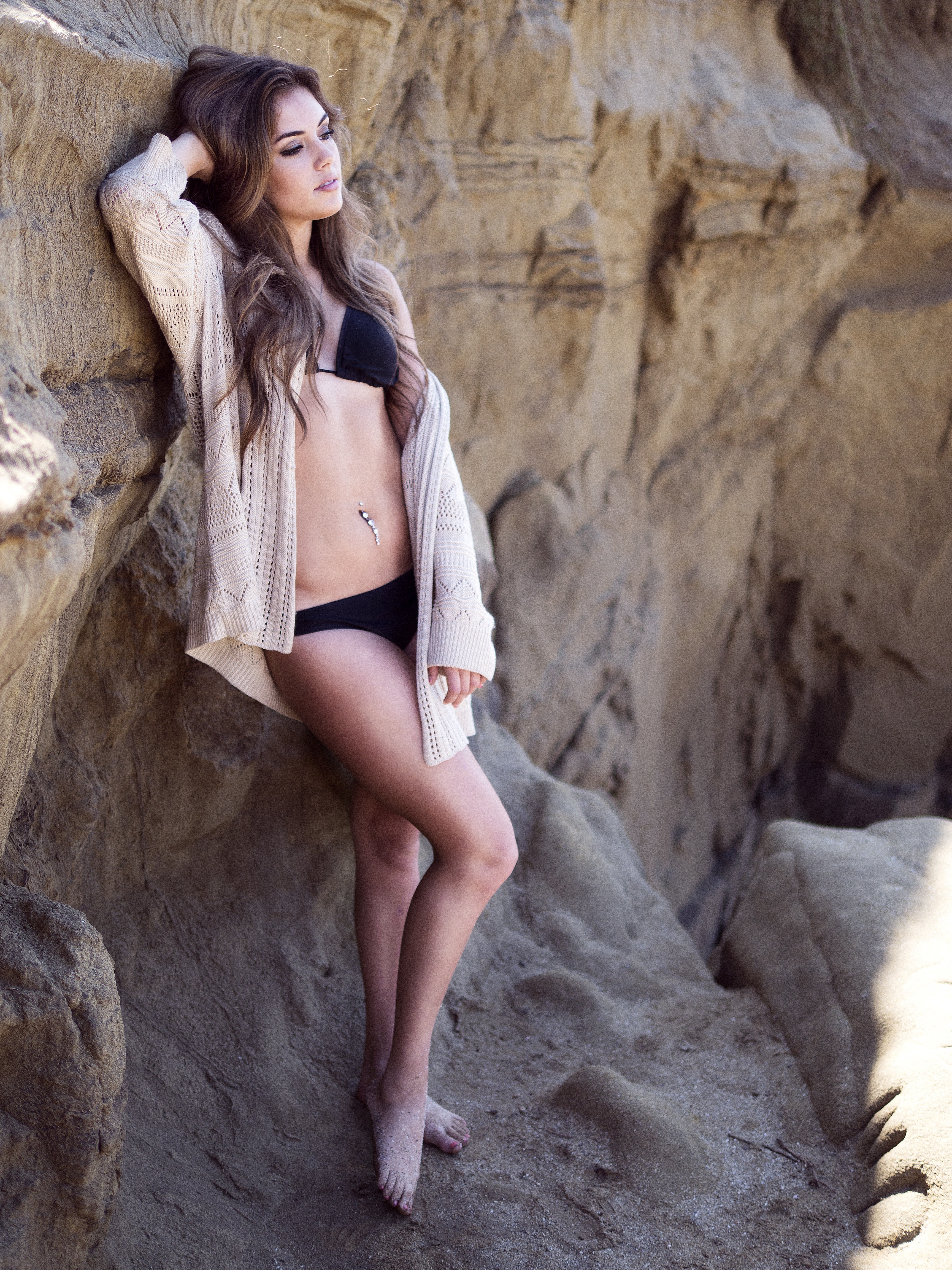 Бесплатное фото Красивая девушка позирует у скалы на берегу моря