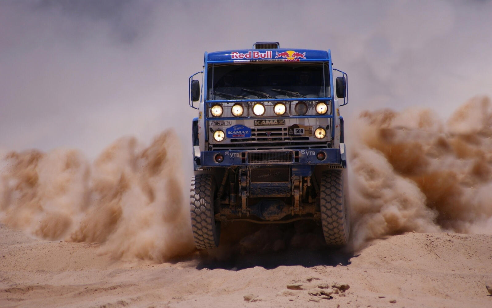 Free photo A Kamaz rally truck driving through the dust.
