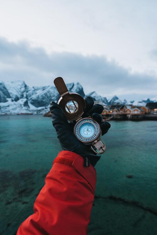 A handheld compass against the ocean
