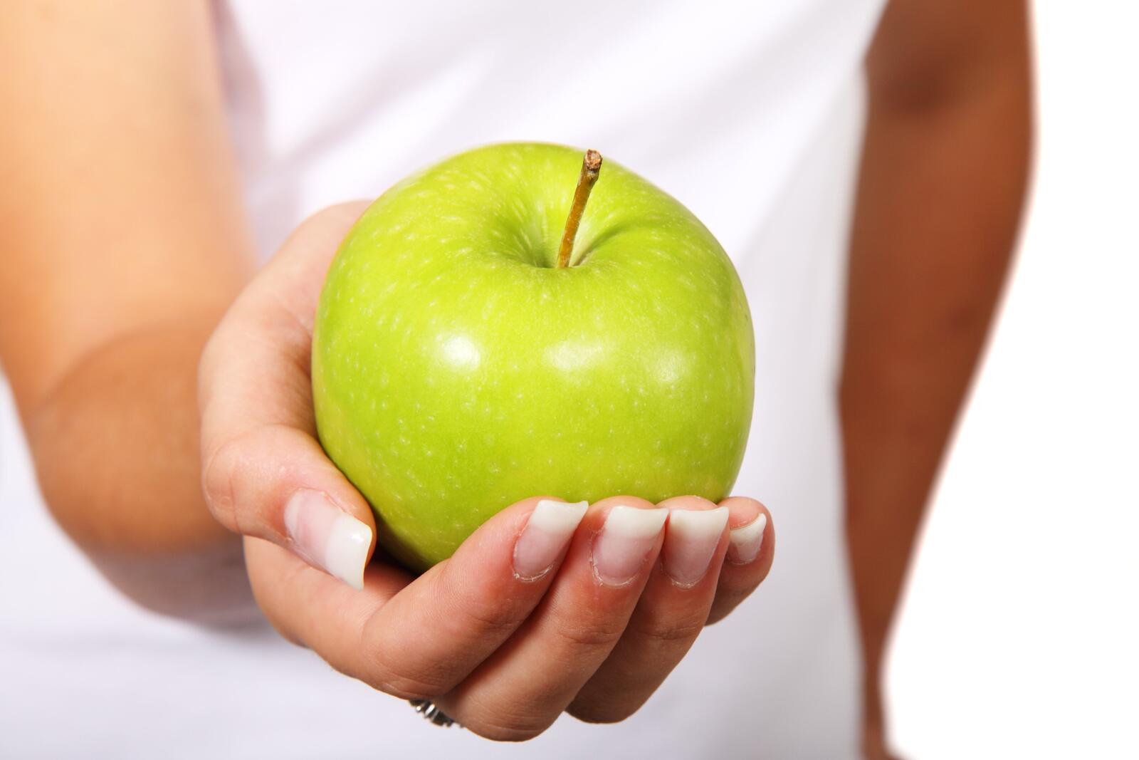Бесплатное фото Зелёное яблоко на ладони