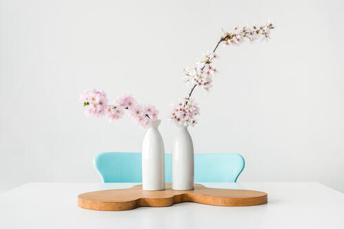 Две вазы с цветами на белом столе