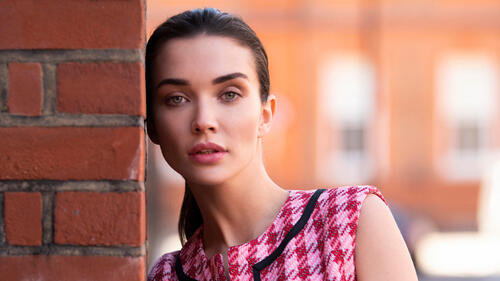 Amy Jackson is standing against a brick wall