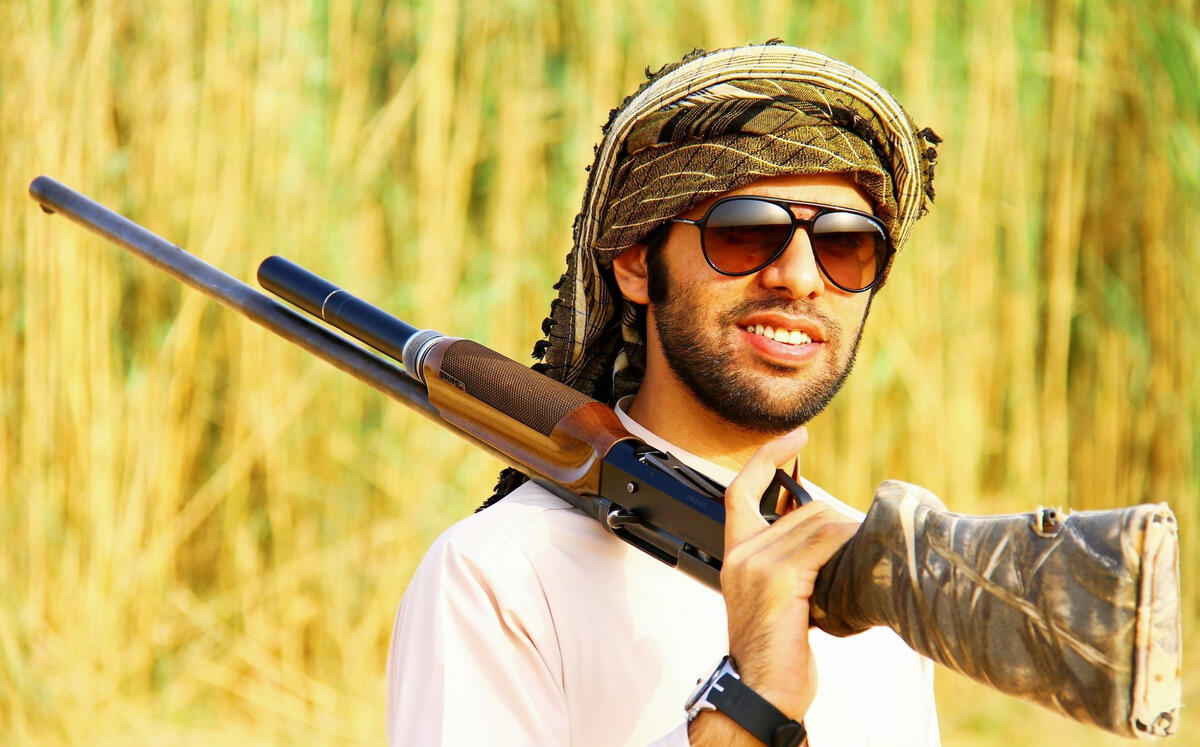 Arab man in sunglasses with a shotgun