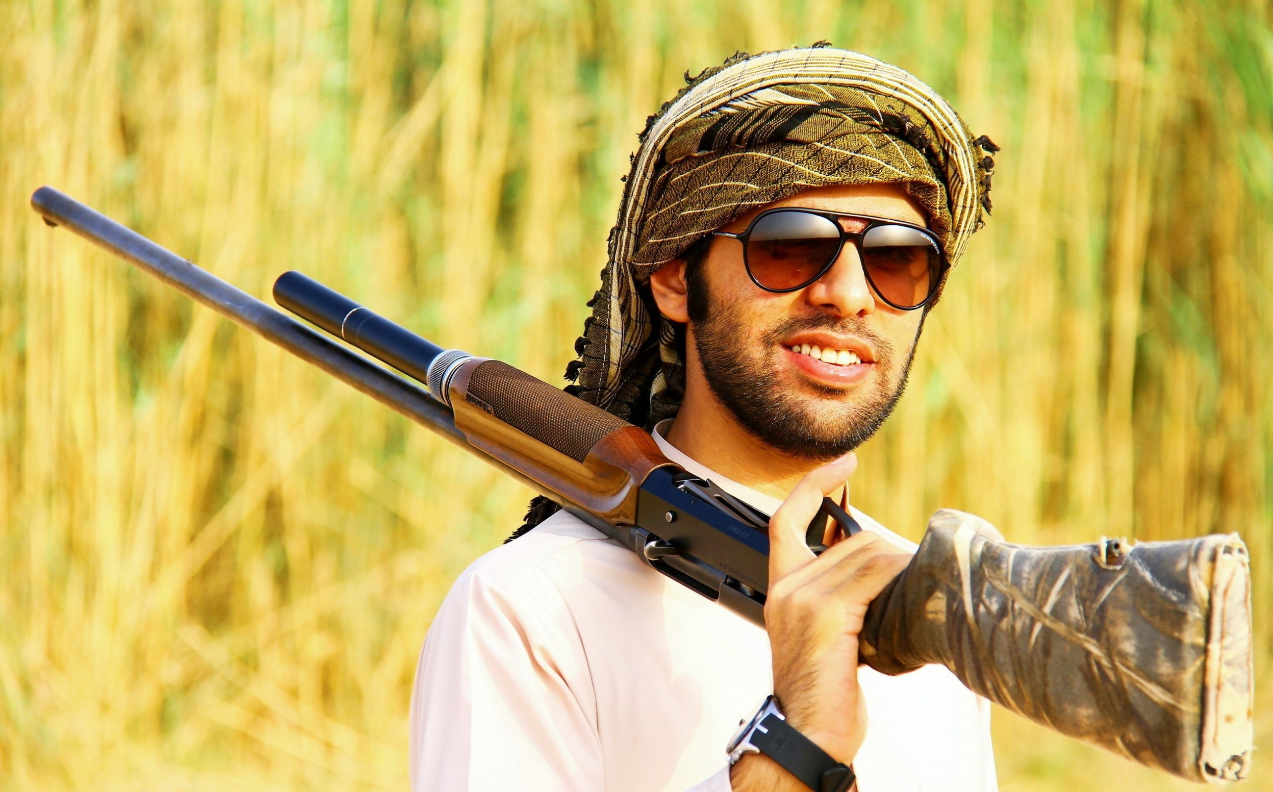 免费照片戴墨镜的阿拉伯男子手持猎枪。