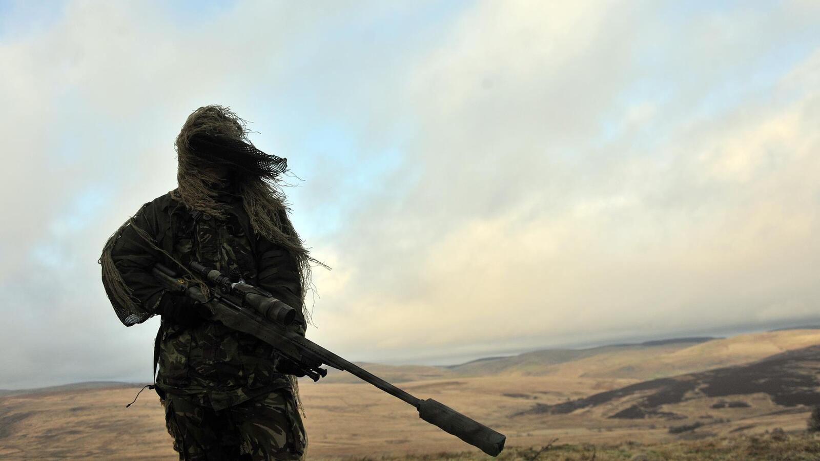 Бесплатное фото Пустынный снайпер с глушителем на винтовке