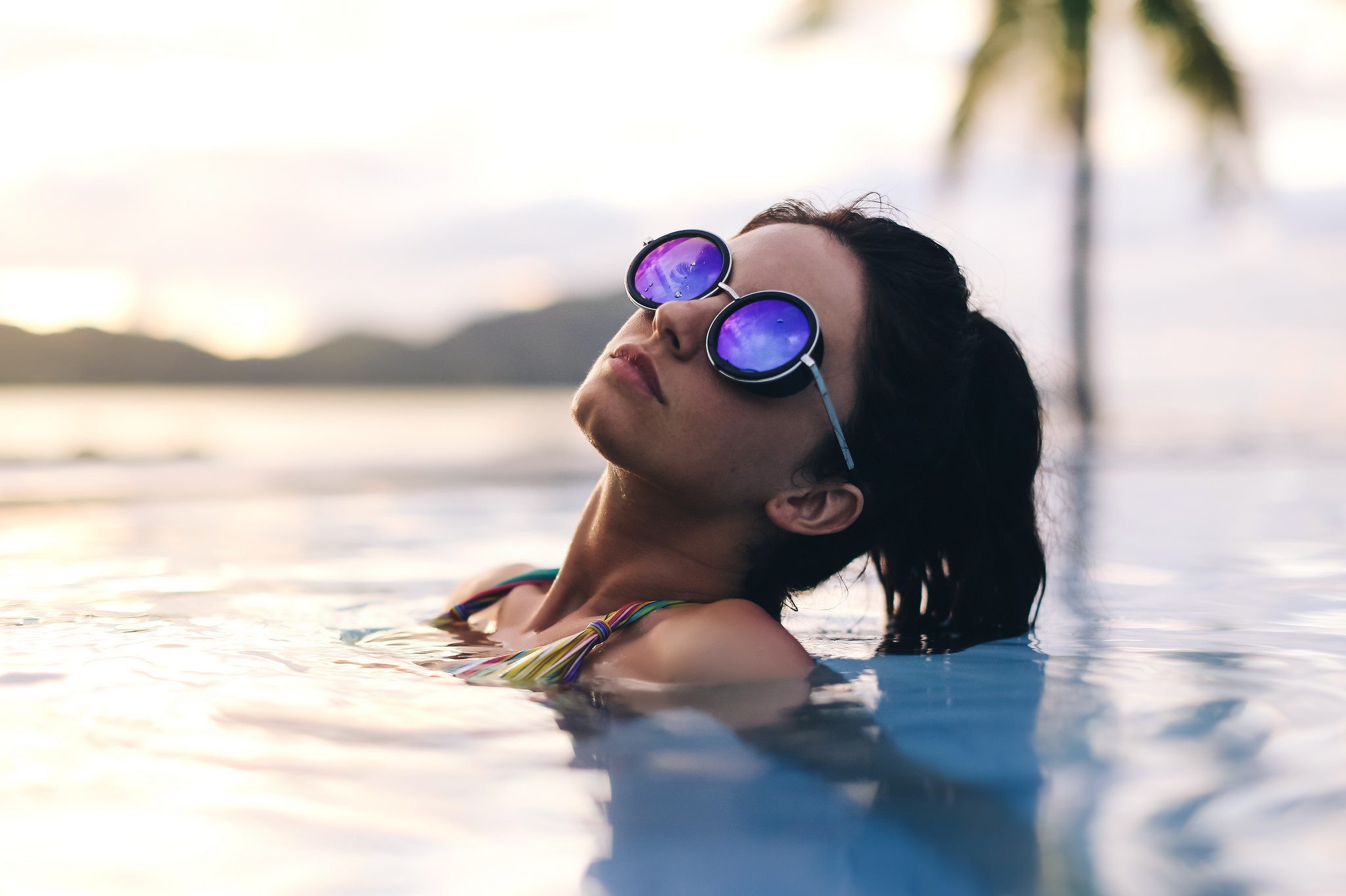 Девушка в солнечных очках отдыхает в бассейне