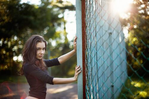 Beautiful brunette standing by the fence