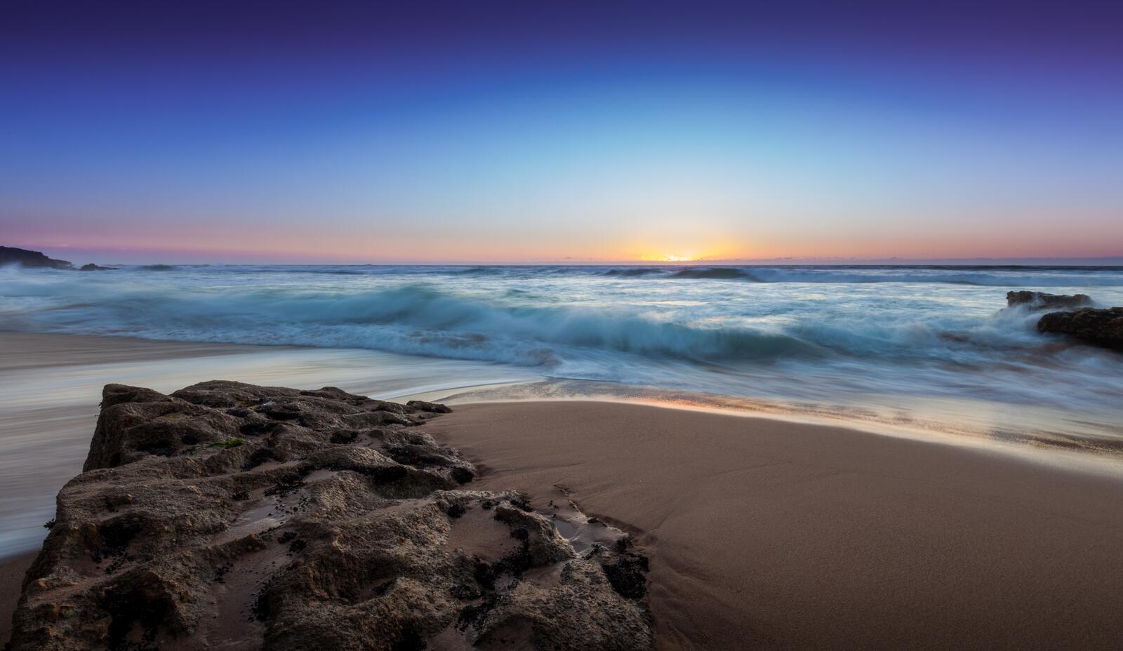 Бесплатное фото Большой камень закопанный в песке на берегу моря
