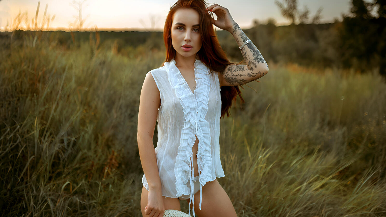 Free photo With a tattoo on her arm undressing in the field.