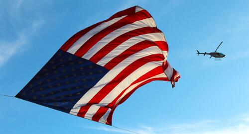天空中的美国国旗在一架路过的直升机面前。