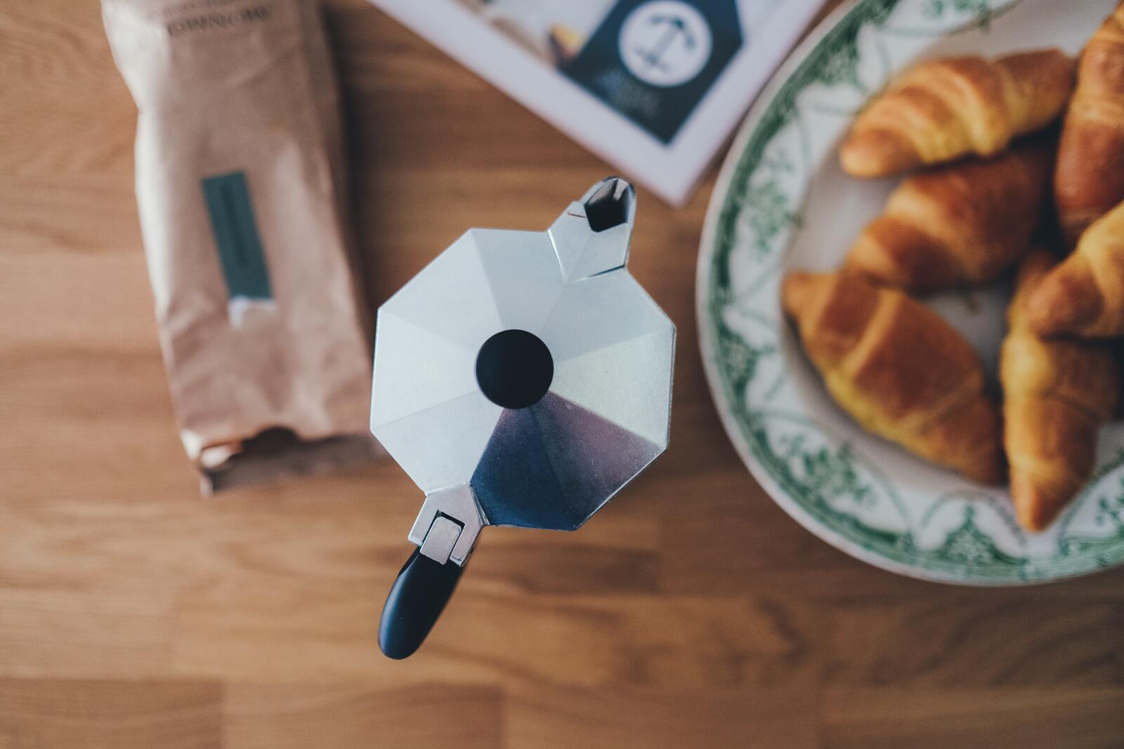 Free photo Teapot with croissants on a wooden table