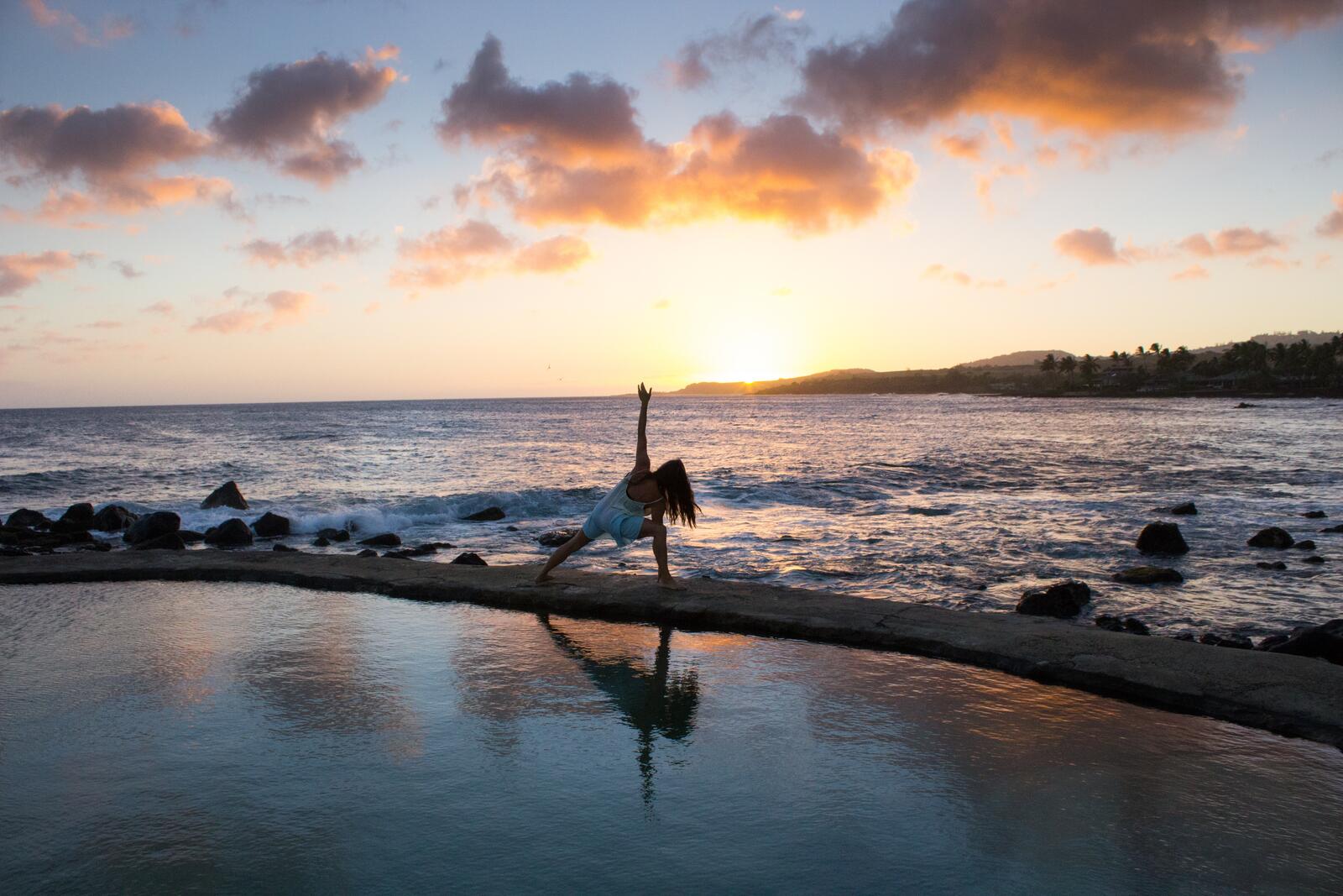 Бесплатное фото Девушка делает зарядку на берегу моря при восходе солнца