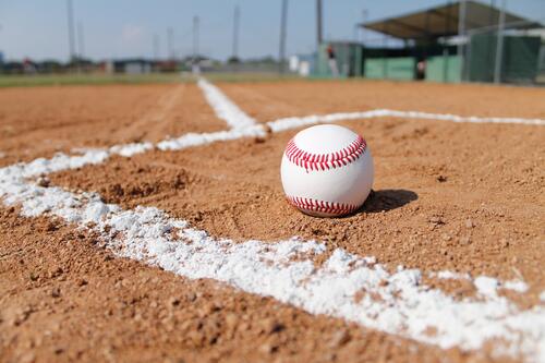 A baseball lies on the red sand