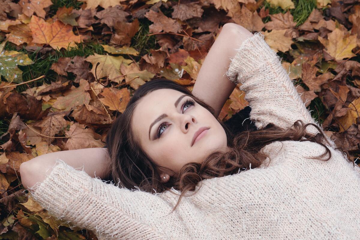 一个黑发女孩躺在落叶上。