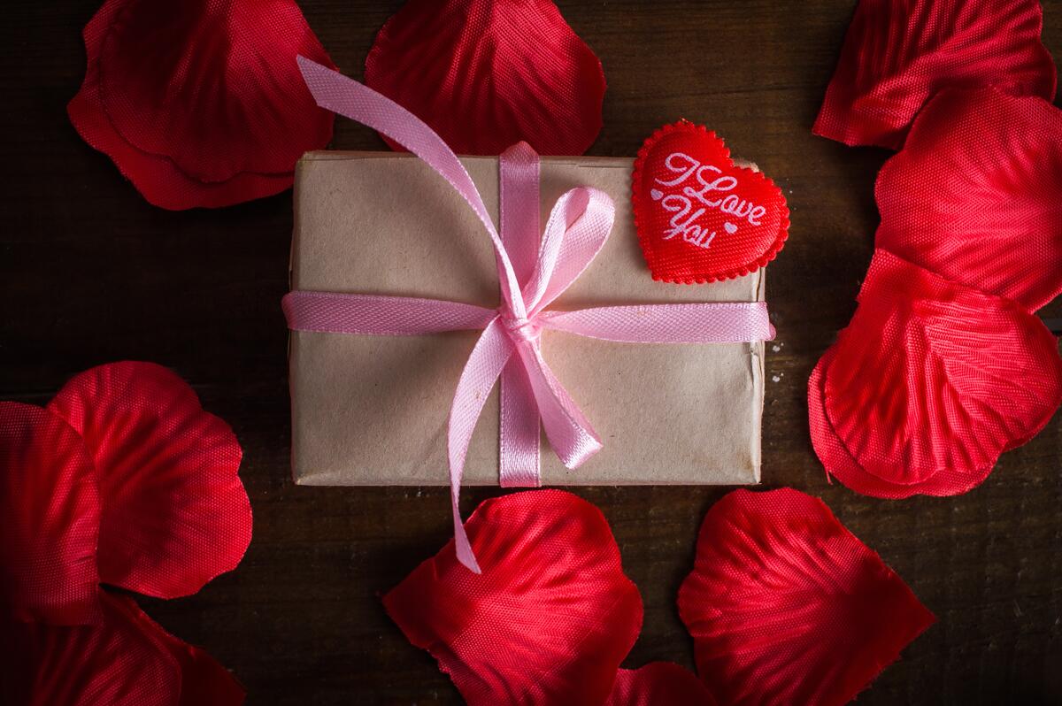 Valentine`s Day gift with red rose petals