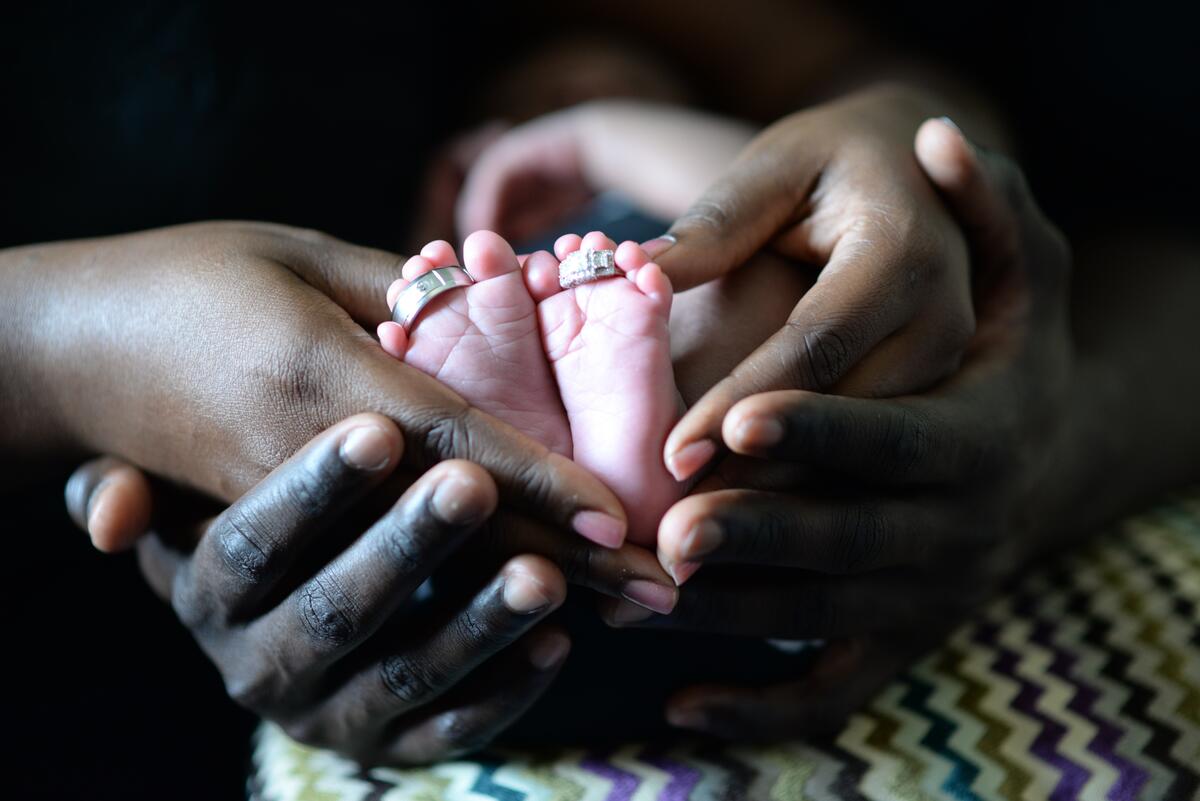 The baby`s feet in the hands of the mother and father
