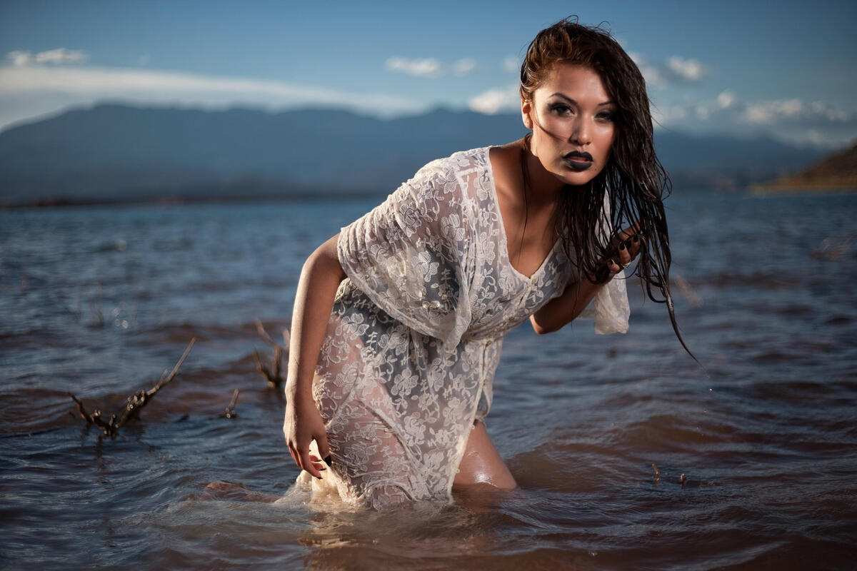 Темноволосая девушка стоит в реке по пояс