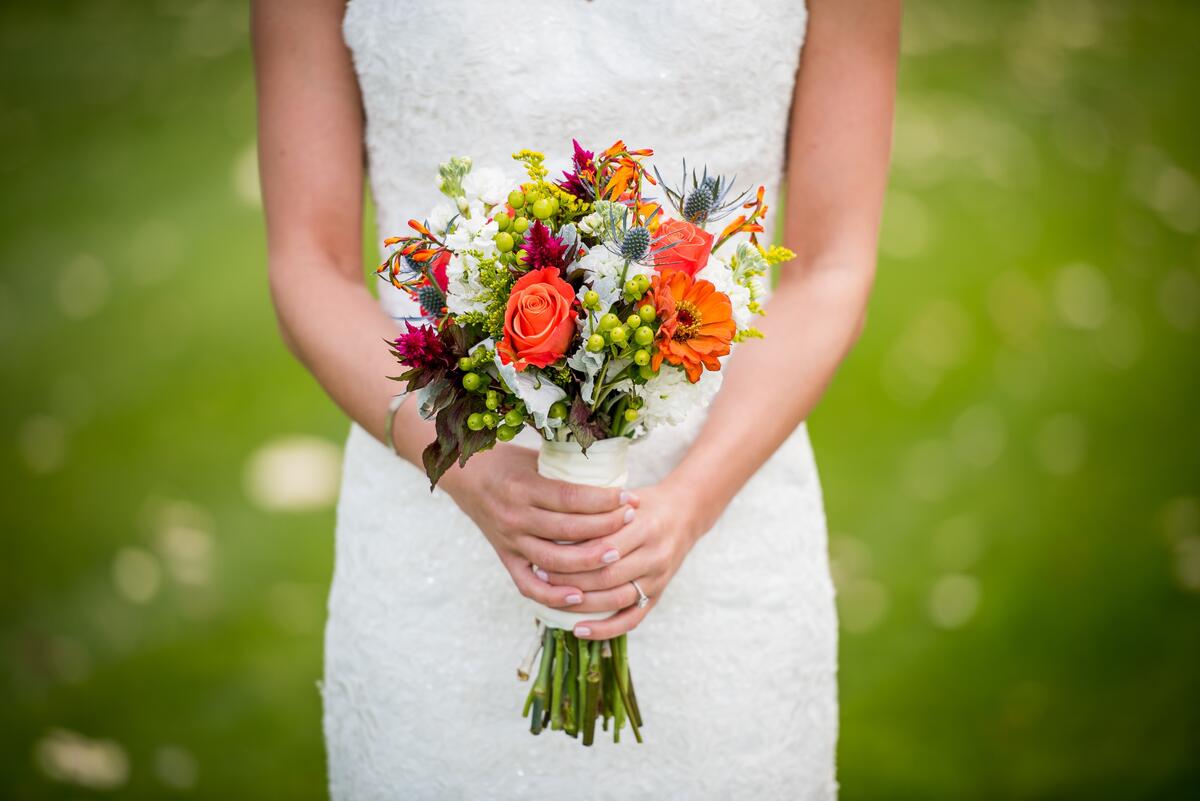 The bride holds a bridal bouquet of flowers
