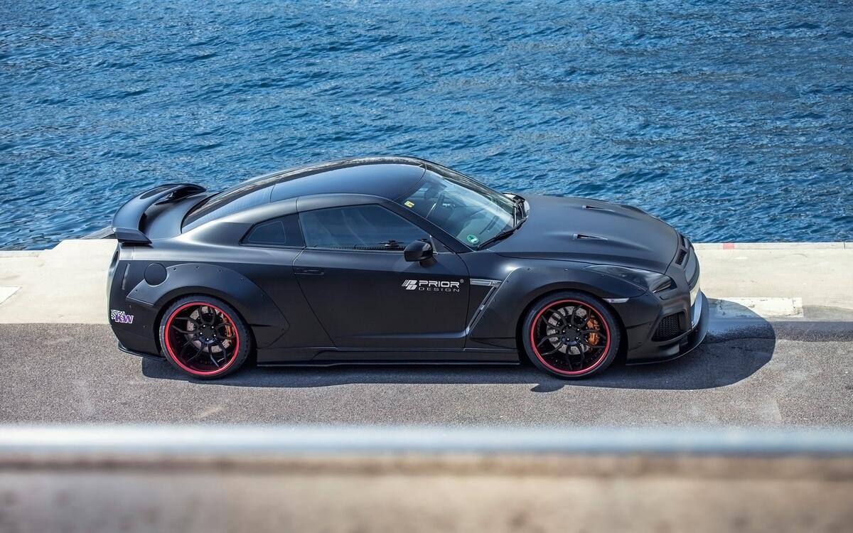 A picture of a black Nissan GT R against the sea.
