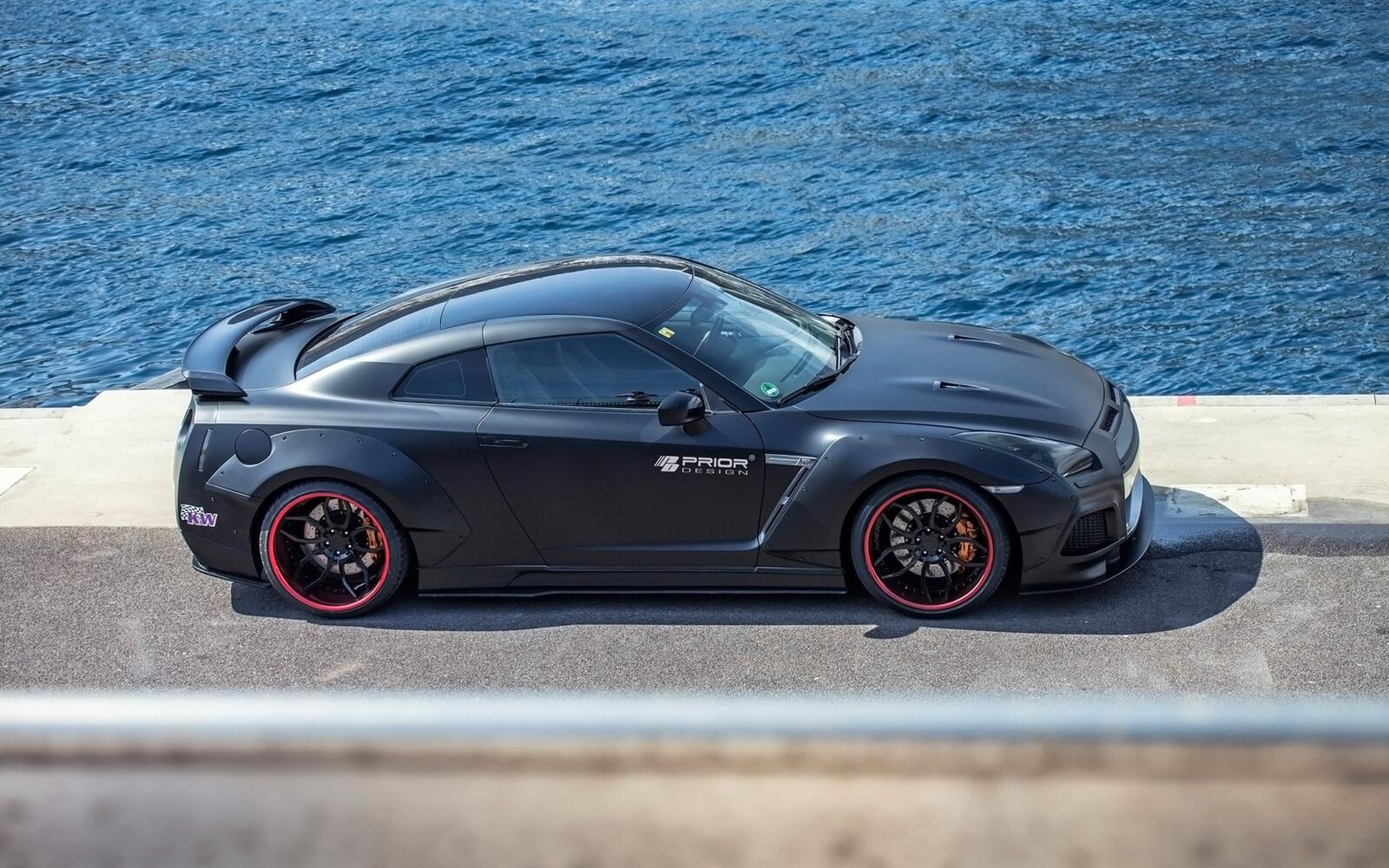 Free photo A picture of a black Nissan GT R against the sea.