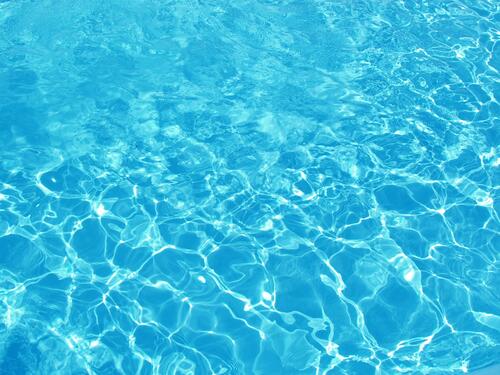 Солнце играет на голубой воде в бассейне