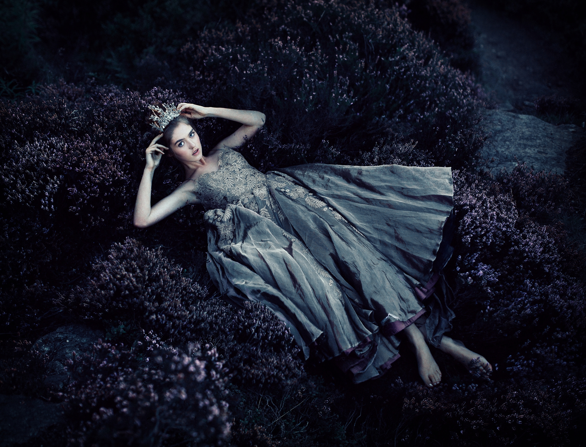 A girl in a dress lying on a bed of flowers