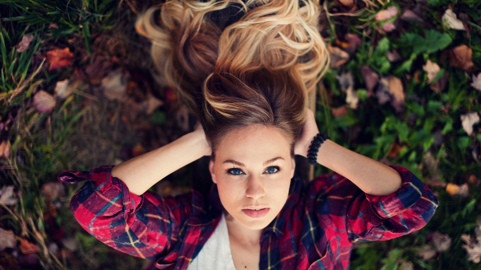 Free photo A girl in a plaid shirt lying on the grass