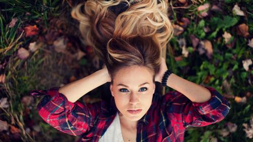 A girl in a plaid shirt lying on the grass