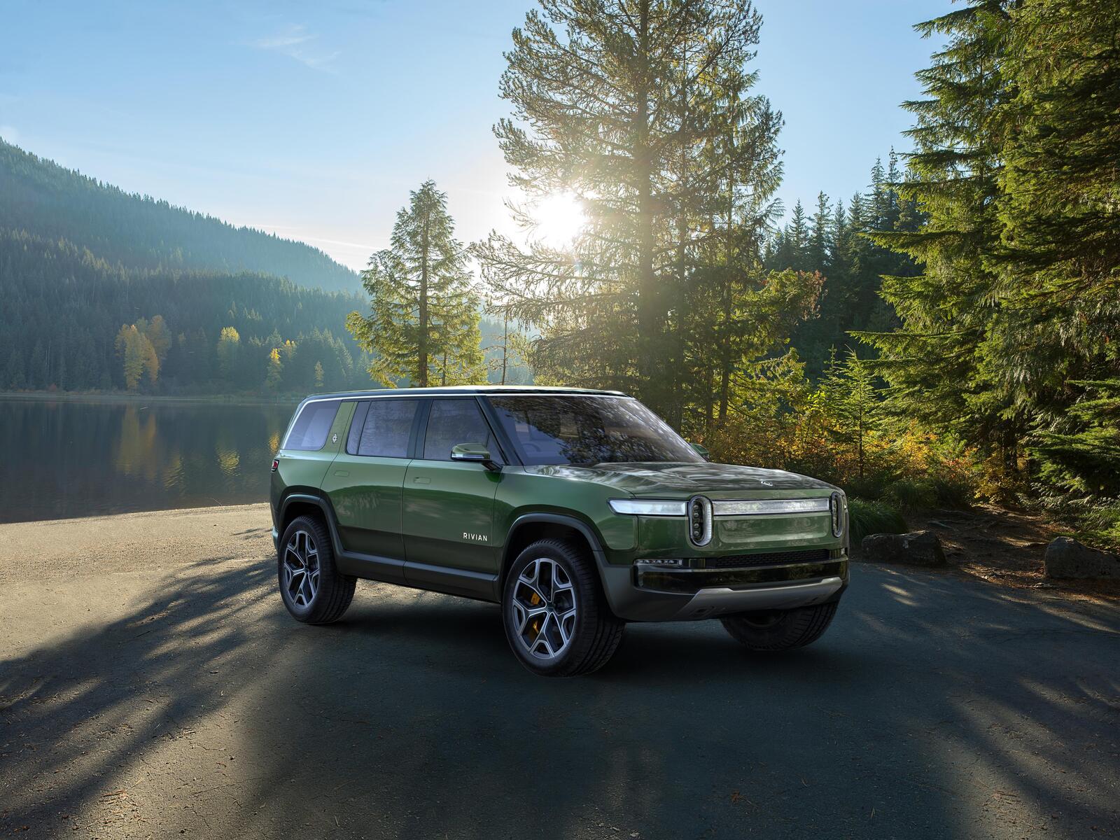 Free photo Rivian R1T electric car of green color stands on the bank of the river