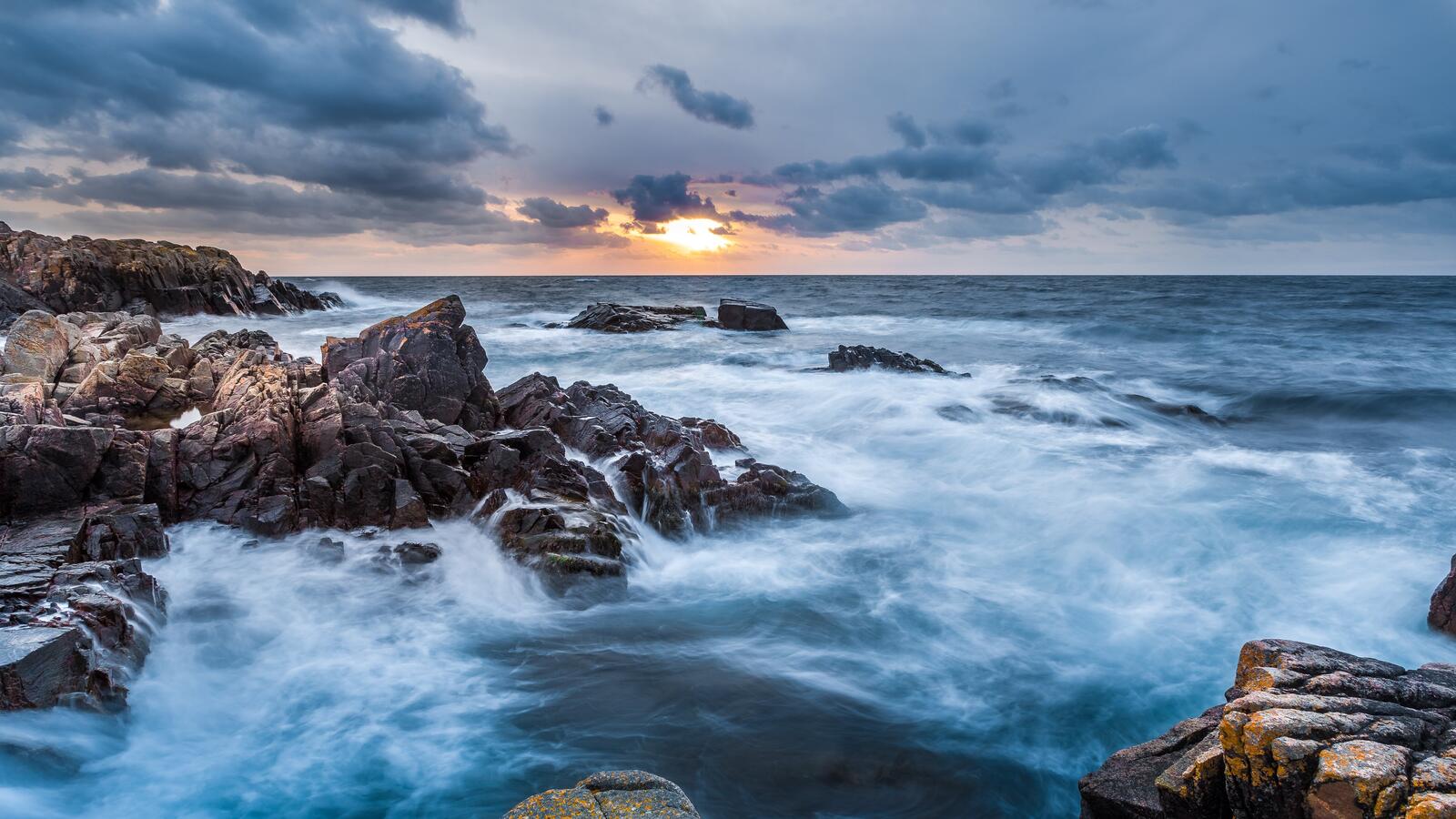 Бесплатное фото Во время восхода волны разбиваются о скалистый берег