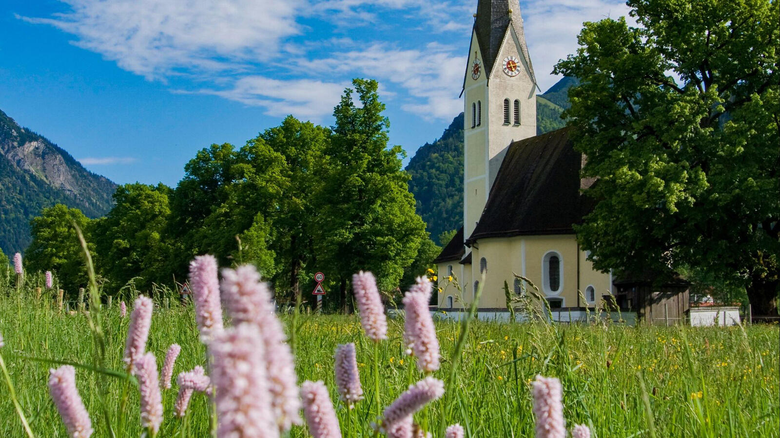 Free photo A church building located near a green forest with mountains