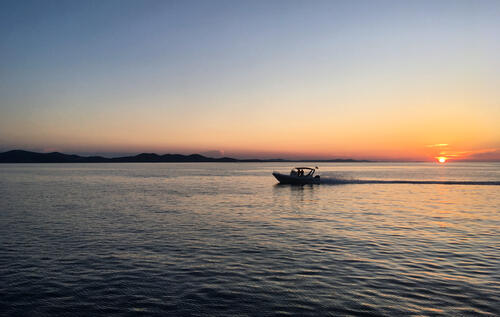 Лодка с мотором плывет по реке при закате солнца