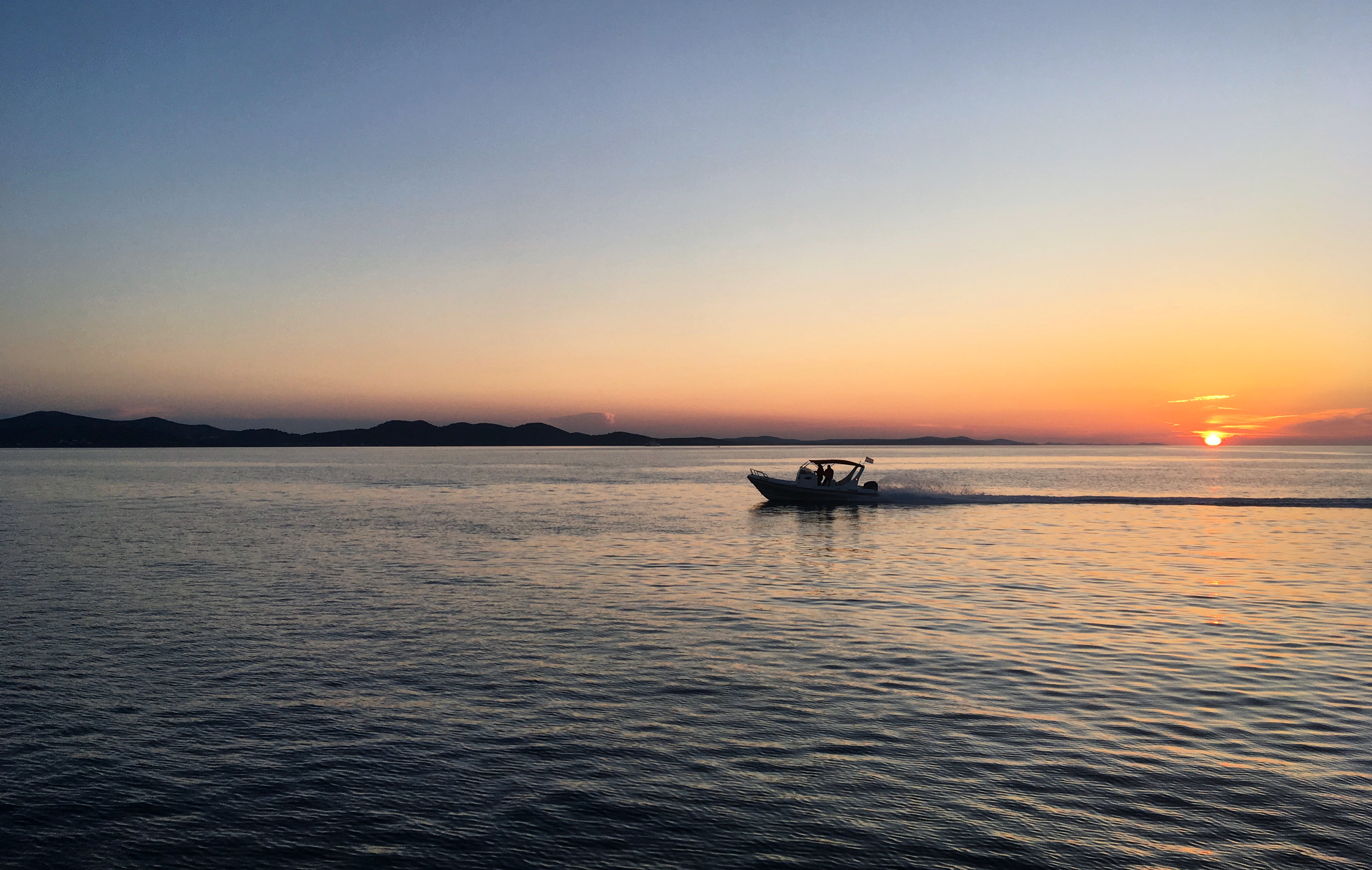 免费照片夕阳下，一艘带马达的船在河上航行