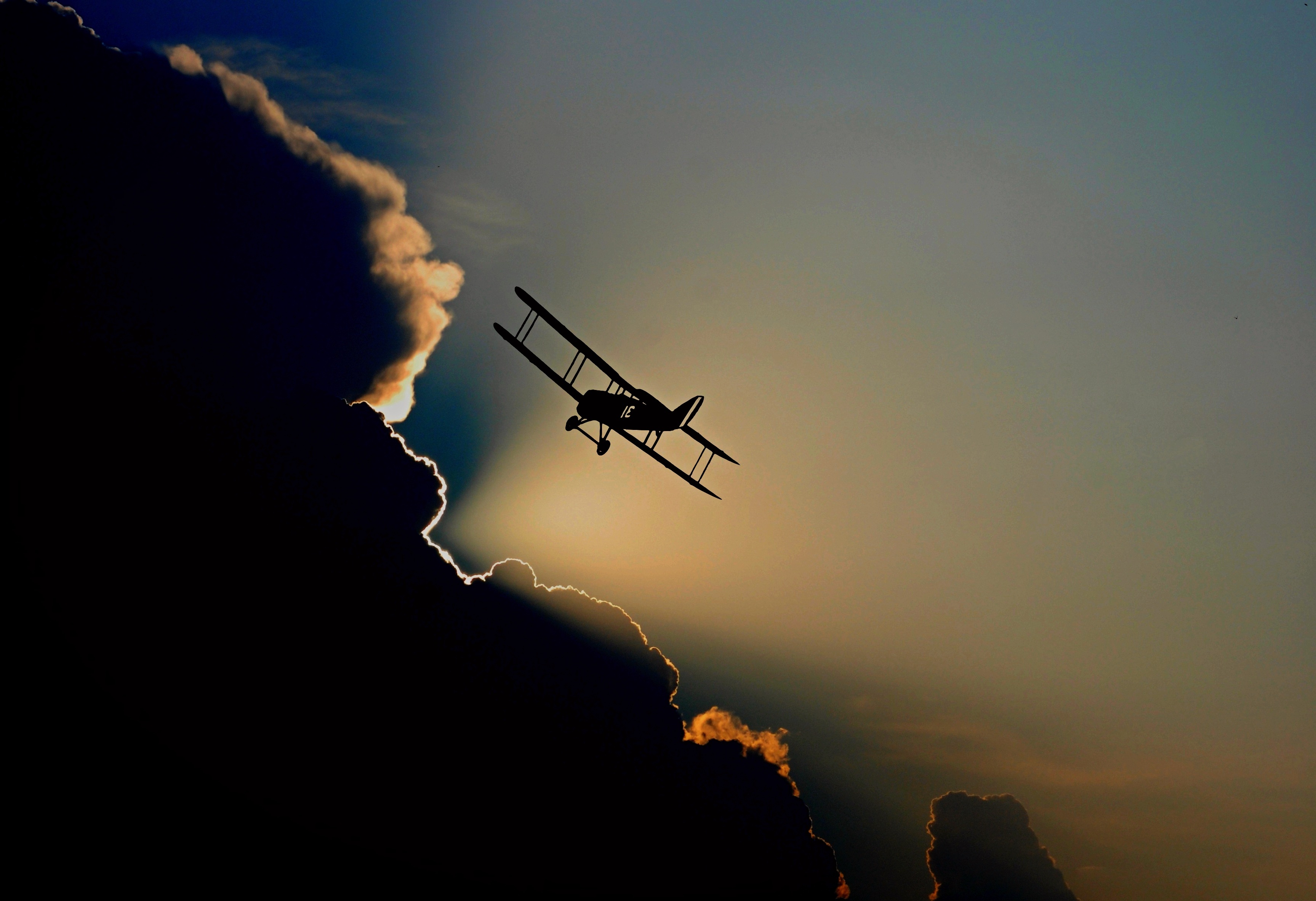 Бесплатное фото Самолет вылетает из облаков на закате